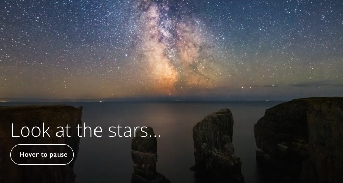 Video still with a “Hover to pause” button. Video shows a starry sky over the sea and caption "Look at the stars"